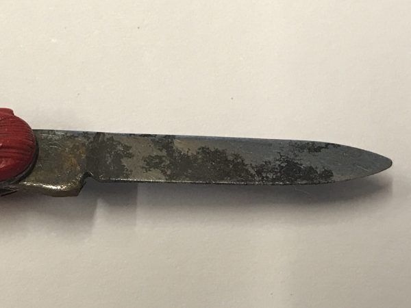 Close-up of the steel blade on a vintage Richards of Sheffield red car pocket knife, 1.5-inch manual blade showing age-related oxidation and patina