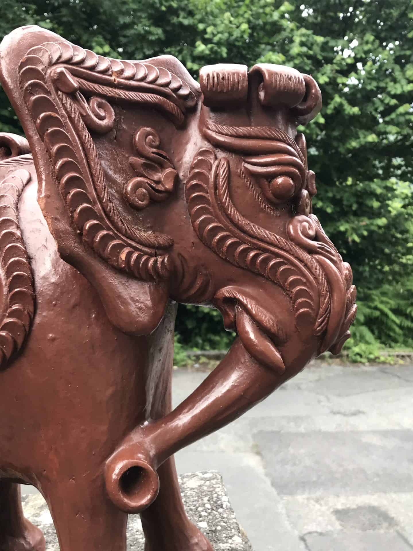 Close-up side view of the head and trunk of a Javanese terracotta elephant moneybox with ornate carved detailing