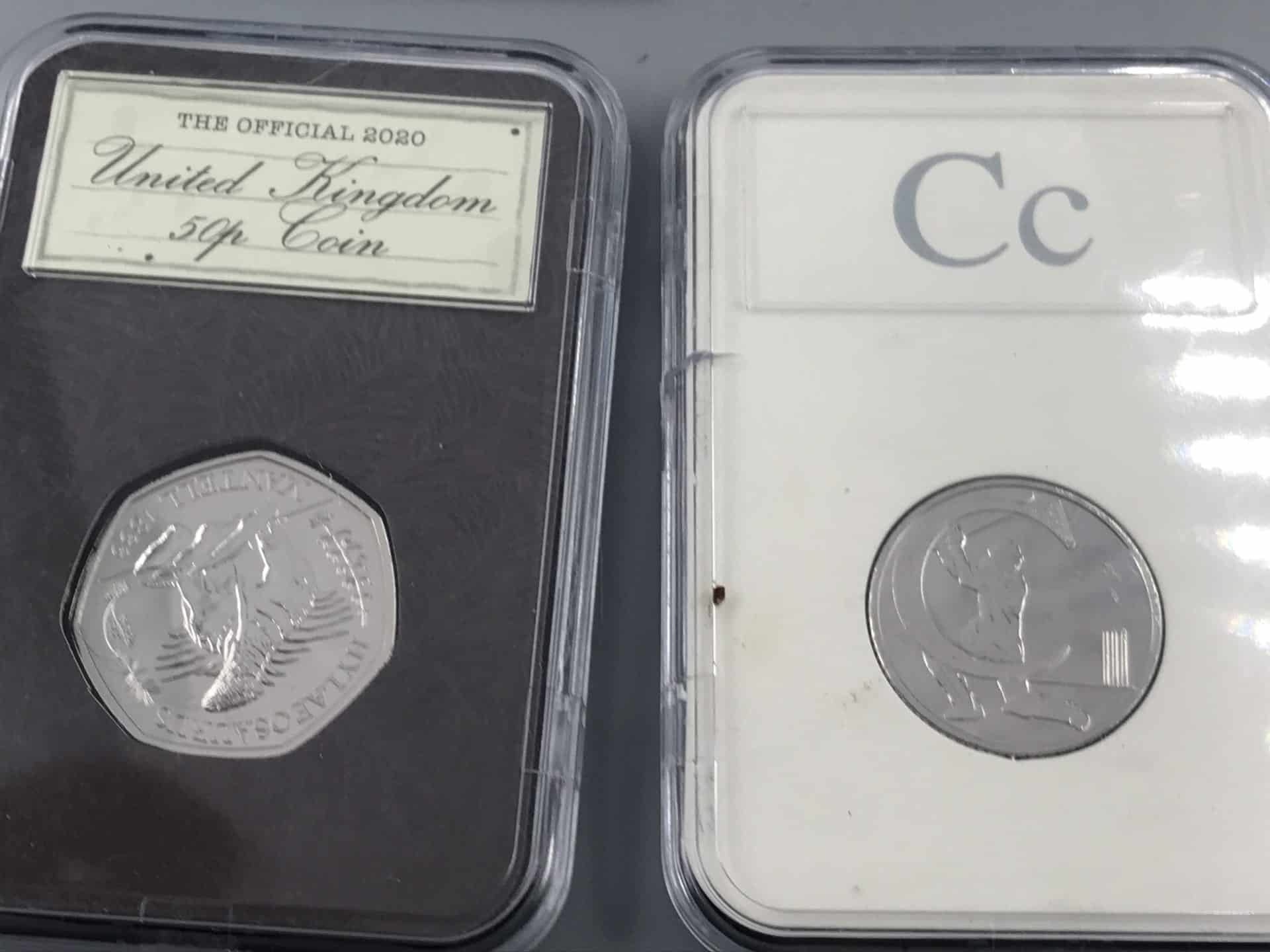 Close-up of two uncirculated UK 50p coins in protective display cases, one labeled “The Official 2020 United Kingdom 50p Coin” and one with “Cc” card insert