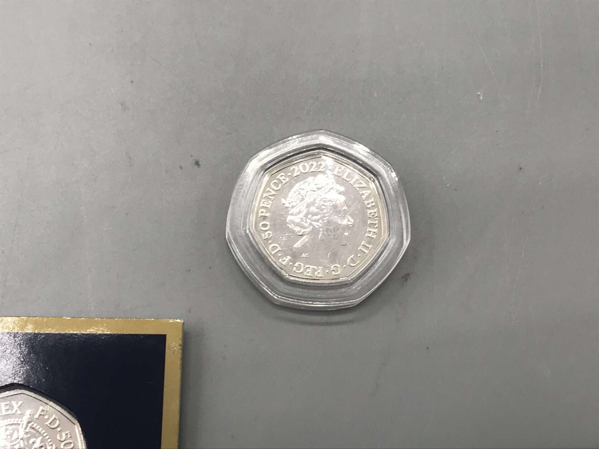 2022 Queen Elizabeth II 50p coin in protective capsule on grey background