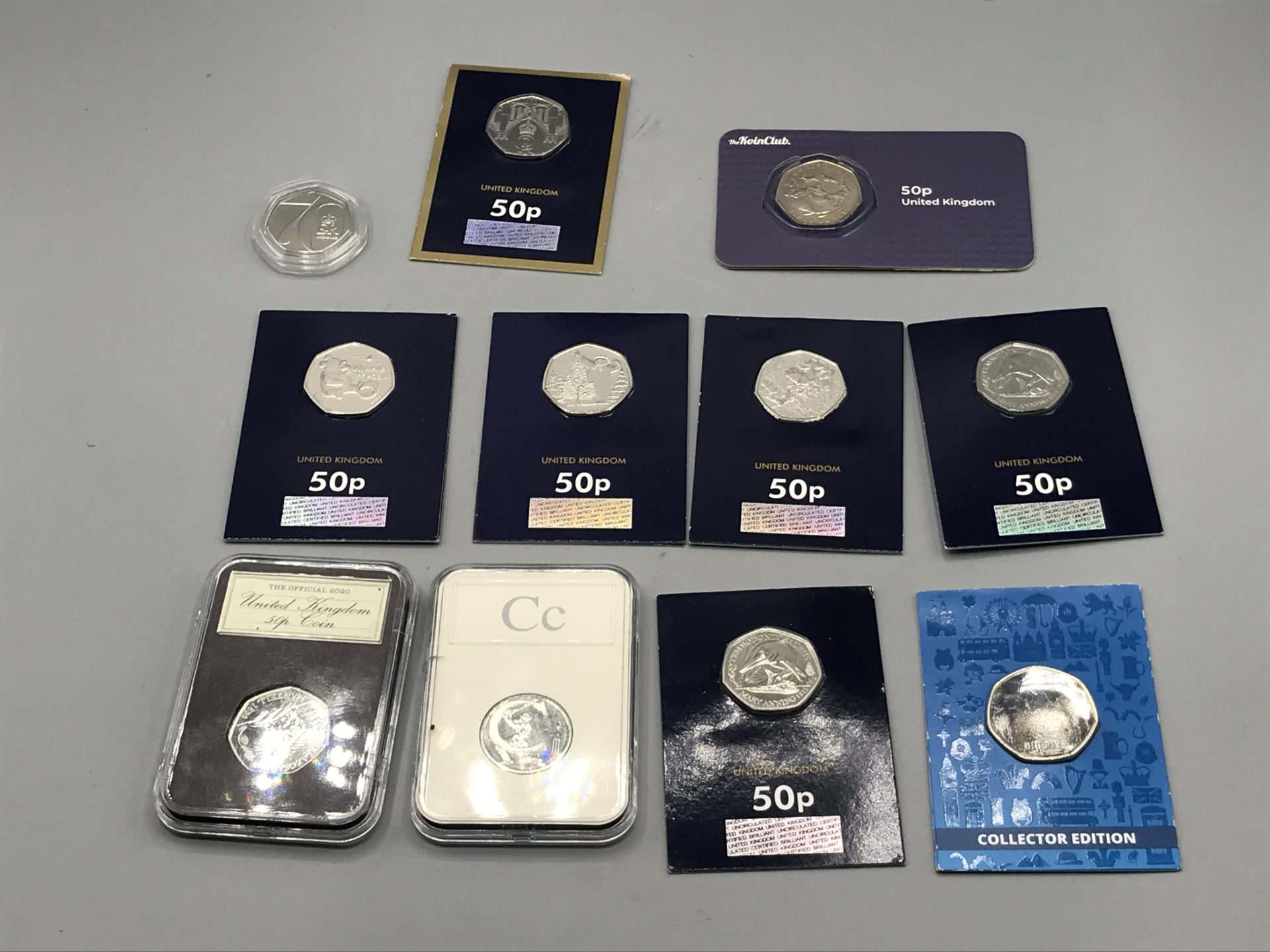 Assorted uncirculated United Kingdom 50p themed coins from 2020–2022 displayed in original packaging, including collector cards and capsules