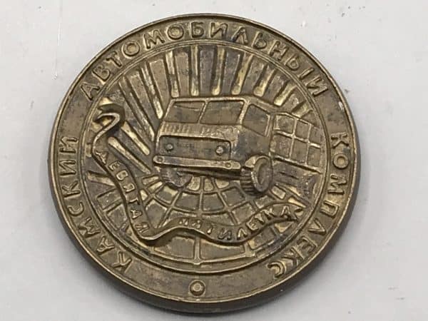 Front view of a bronze KAMAZ commemorative medallion featuring a truck design and Cyrillic text.
