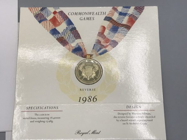 Reverse view of the 1986 Royal Mint £2 Commonwealth Games coin in original presentation folder, showing thistle design and coin specifications
