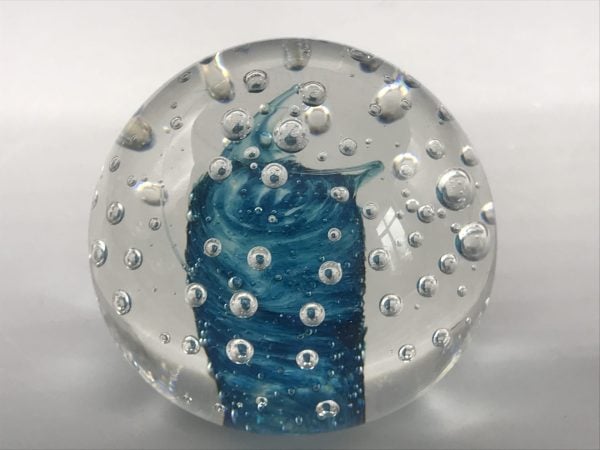 Angled view of a Murano glass paperweight with a blue swirl core and suspended air bubbles within clear glass