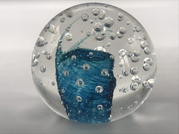 Close-up of a Murano glass paperweight showing detailed blue swirl core and air bubbles suspended in clear glass