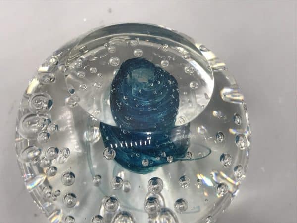 View of the base of a Murano glass paperweight showing the swirl formation from beneath with trapped air bubbles in clear glass