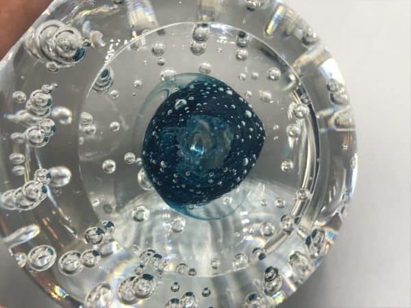 Close-up view of the base of a Murano glass paperweight showing the tight swirl core and suspended bubbles through thick clear glass