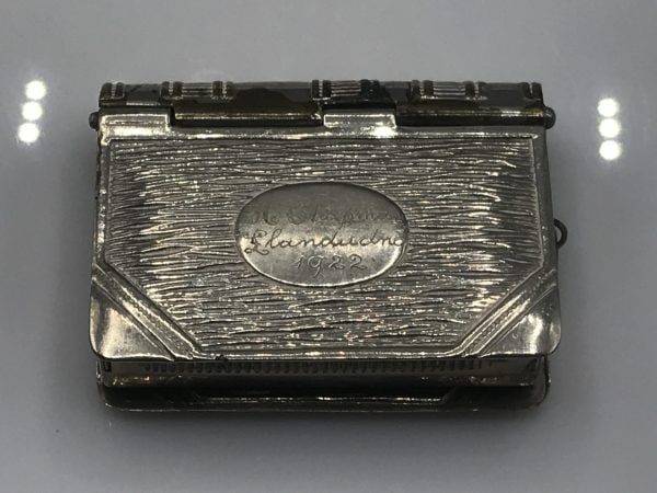 Front view of an antique silver book-form vesta case with an oval engraved plaque dated 1922.