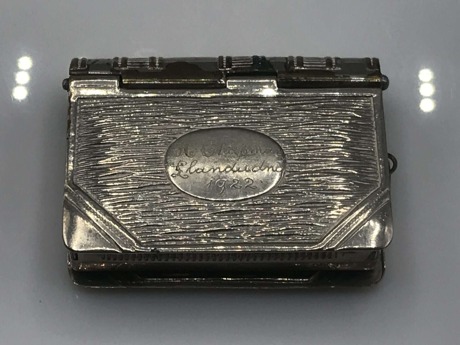 Front view of an antique silver book-form vesta case with an oval engraved plaque dated 1922.