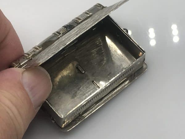 Open view of an antique silver plate book-form vesta case showing the interior compartment and hinged lid.