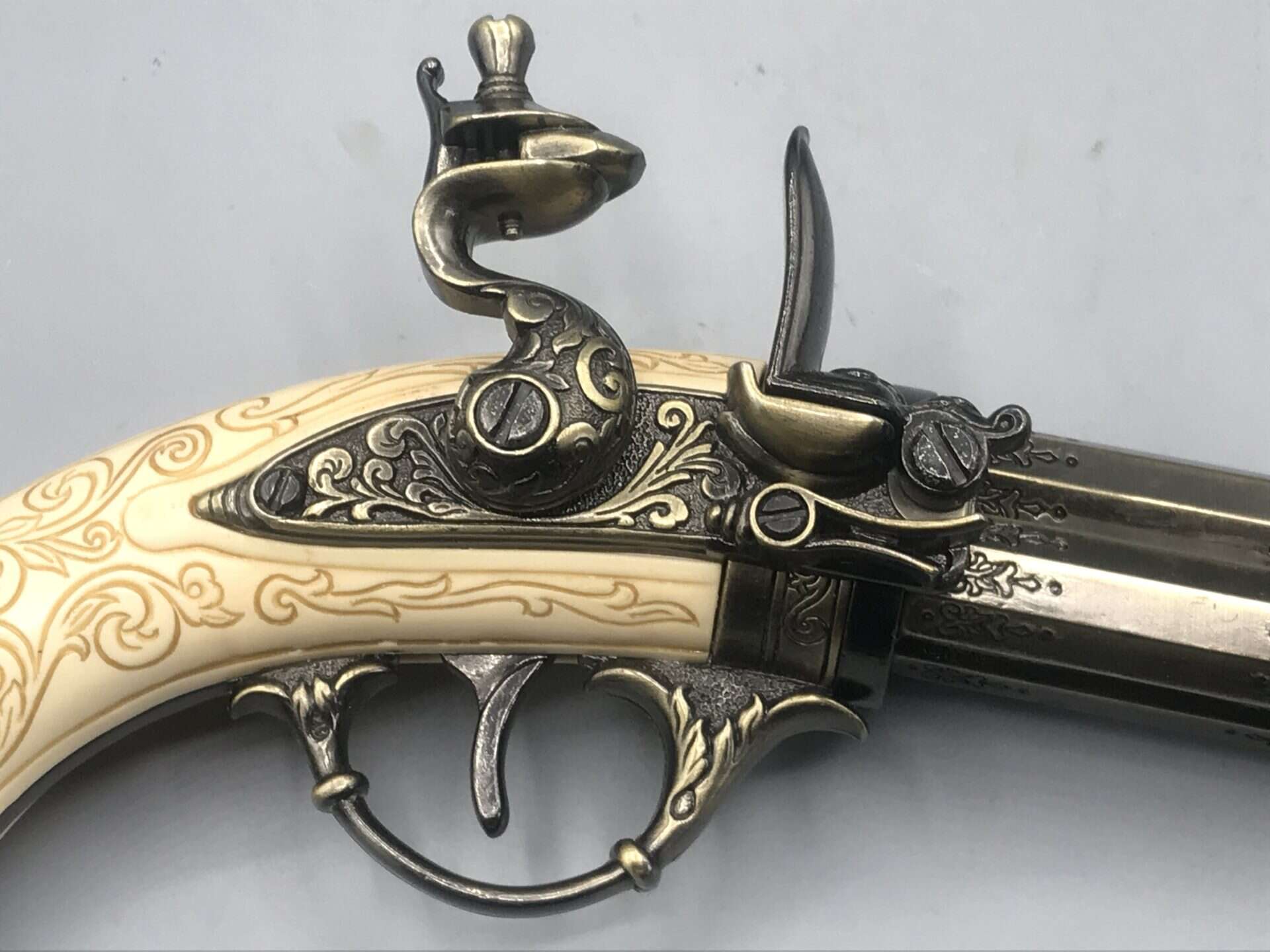 Close-up of flintlock firing mechanism on replica 18th-century pistol, showing hammer, frizzen, and detailed metalwork.