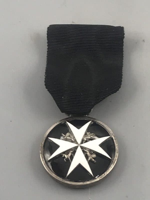 Front view of a St John Ambulance medal featuring a white Maltese cross on black enamel, suspended from a black ribbon