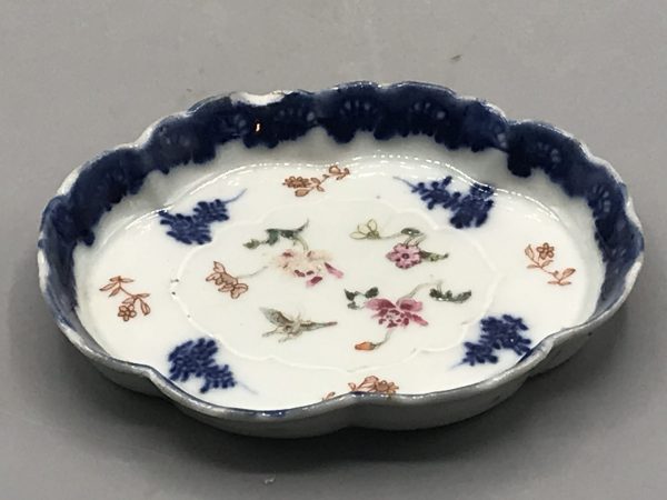 18th century Chinese export porcelain dish from the Qianlong period with scalloped rim, underglaze blue border, and famille rose floral and butterfly decoration, measuring 5 x 3.75 x 0.5 inches