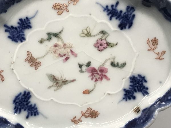 Close-up of interior decoration on 18th century Chinese export porcelain dish, Qianlong period, showing famille rose floral sprays, butterfly motif, and fine hairline crack in the glaze
