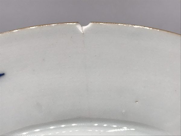 Close-up of small rim chip with tight hairline crack on 18th century Chinese export porcelain plate, Imari style, Jingdezhen kiln