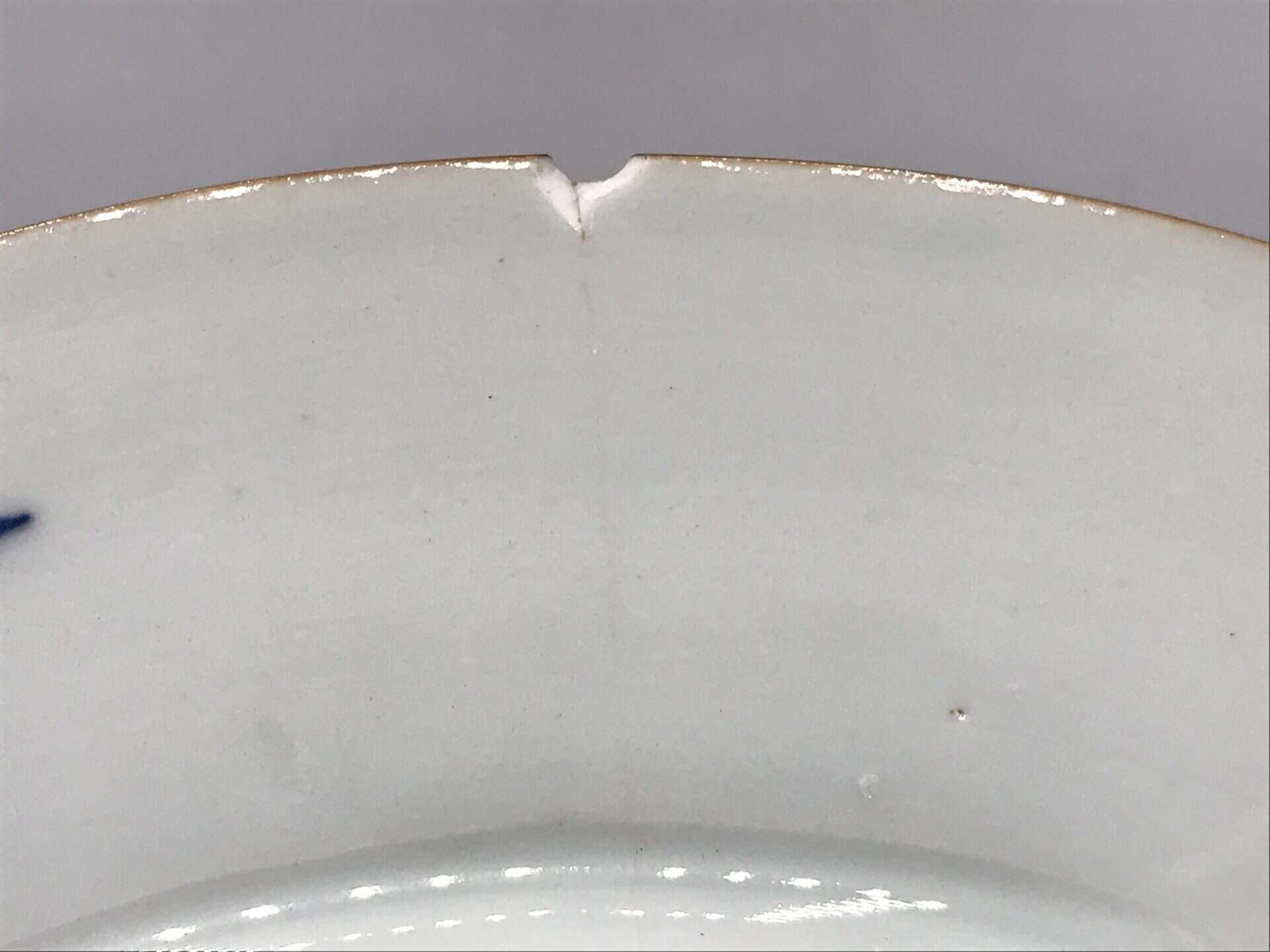 Close-up of small rim chip with tight hairline crack on 18th century Chinese export porcelain plate, Imari style, Jingdezhen kiln