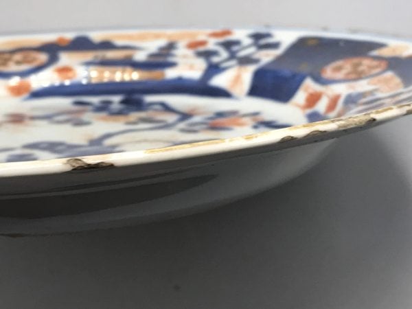 Close-up of rim fretting on 18th century Kangxi Chinese Imari porcelain plate, showing age-related wear and glaze loss