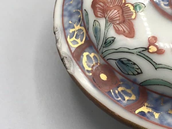 Close-up view of rim chips on domed lid from 18th century Kangxi Chinese porcelain teapot with famille verte floral decoration