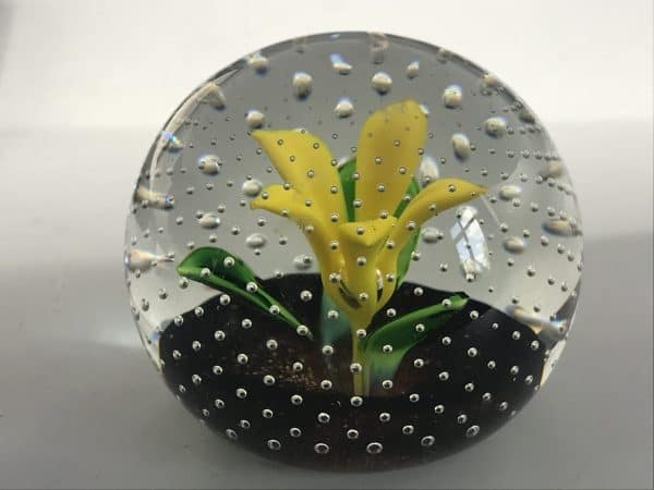 Side view of Caithness “Flower in Rain” lampwork paperweight with yellow flower and controlled bubbles