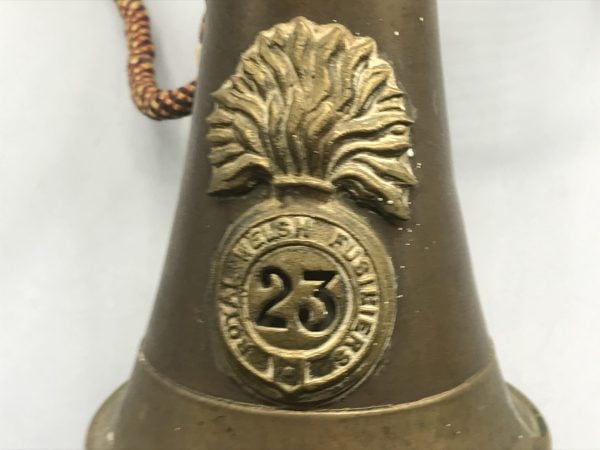 Close-up of brass badge on antique Royal Welch Fusiliers 23rd Regiment bugle, featuring flaming grenade emblem