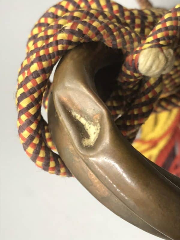 Close-up of dent on the bend of antique brass and copper Royal Welch Fusiliers bugle