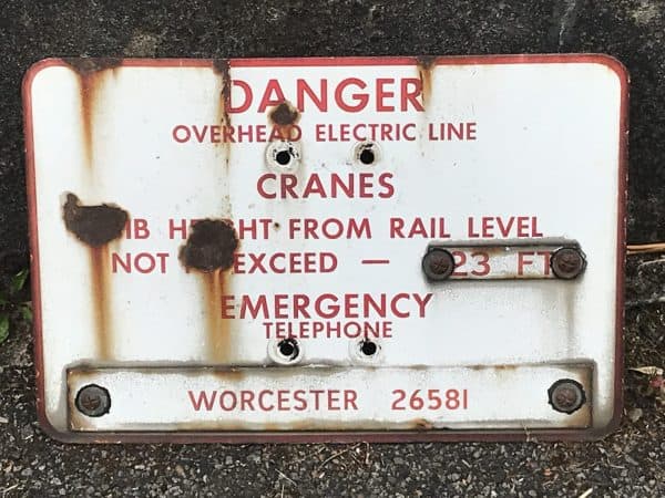 Antique enamel railway warning sign, mid-20th century industrial hazard notice in red and white, reading “Danger Overhead Electric Line” with emergency telephone details, 12 x 18 inches