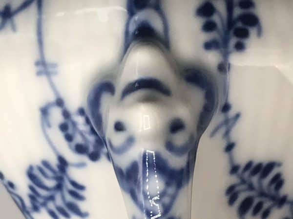 Close-up of figural mask detail on Royal Copenhagen Blue Fluted Lace cream jug, located at base of handle