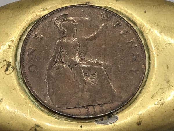 Close-up of a 1916 British copper penny inset into the lid of a brass snuff box.