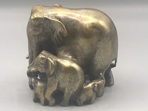 Early 20th-century Indian antique brass elephant family sculpture side view showing central matriarch with surrounding calves, traces of original silver wash, approx. 3.75 inches tall