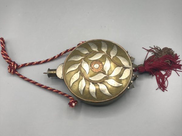 Antique Moroccan brass cantimplora flask with silver and copper inlay, floral and leaf motif, red tassel and cord, measuring 7 inches including spout