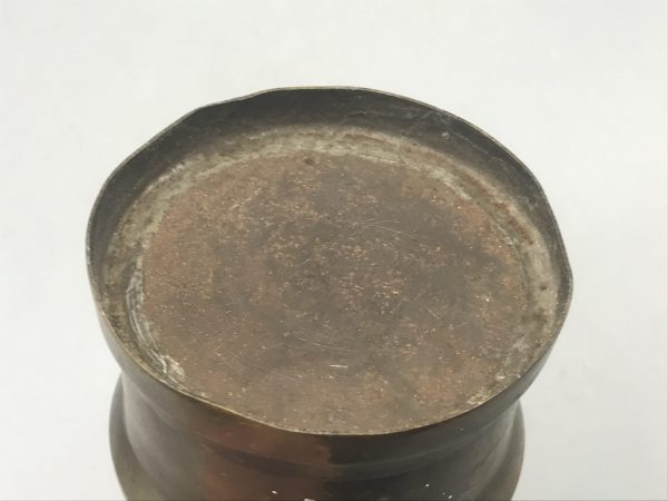 Underside view of antique brass and steel coal miner’s midget safety lamp showing aged base with patina and wear.