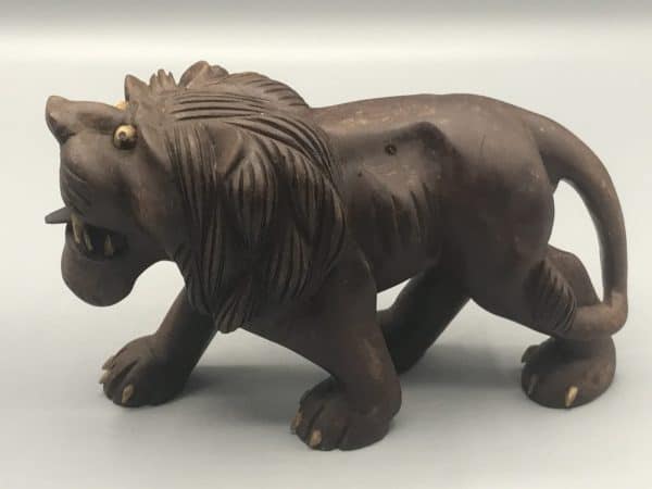 Side profile of a carved wooden Chinese guardian lion, or foo dog, showing detailed mane, open mouth, and curved tail, approximately 7 inches long.