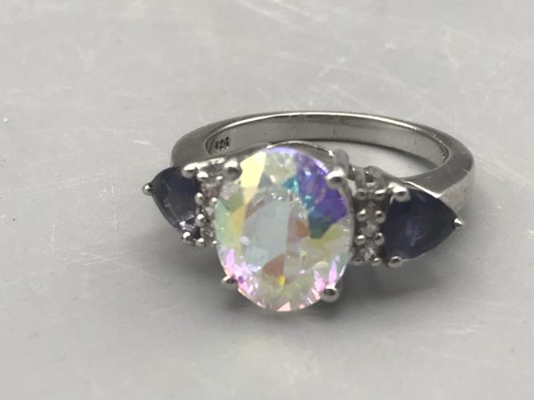 Sterling silver TGGC ring featuring an oval mystic quartz center stone with rainbow hues and two pear-cut blue accent stones, UK ring size O.