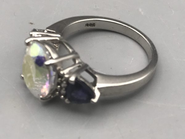 Side view of sterling silver TGGC ring featuring an oval mystic quartz center stone and blue pear-cut accents, showing “925” hallmark inside band.