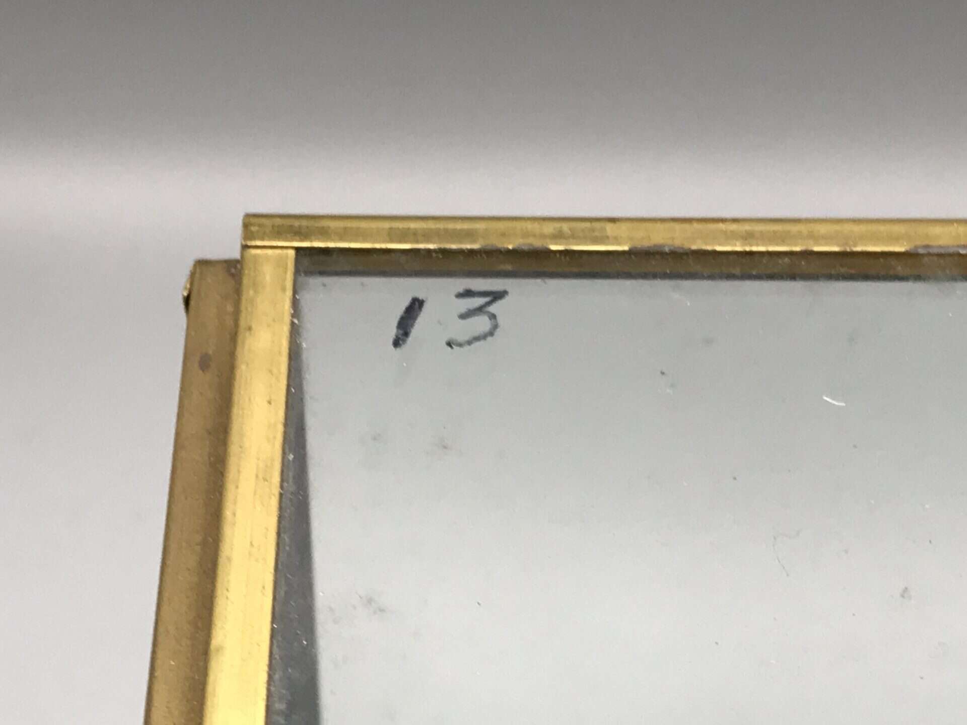 Close-up of number “13” handwritten in marker on the brass and glass display case of the Danbury Mint 1938 Rolls-Royce Phantom III model