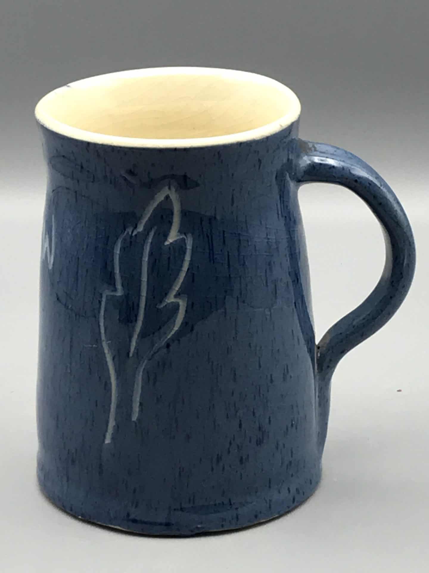 Blue stoneware tankard by Claypits Pottery Ewenny, featuring incised leaf motif and cream interior, approximately 5.5 inches tall.