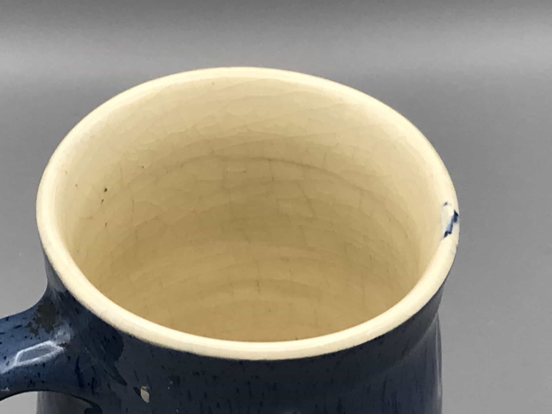 Close-up of the rim and interior of blue stoneware tankard by Claypits Pottery Ewenny, showing cream glaze and fine crazing.