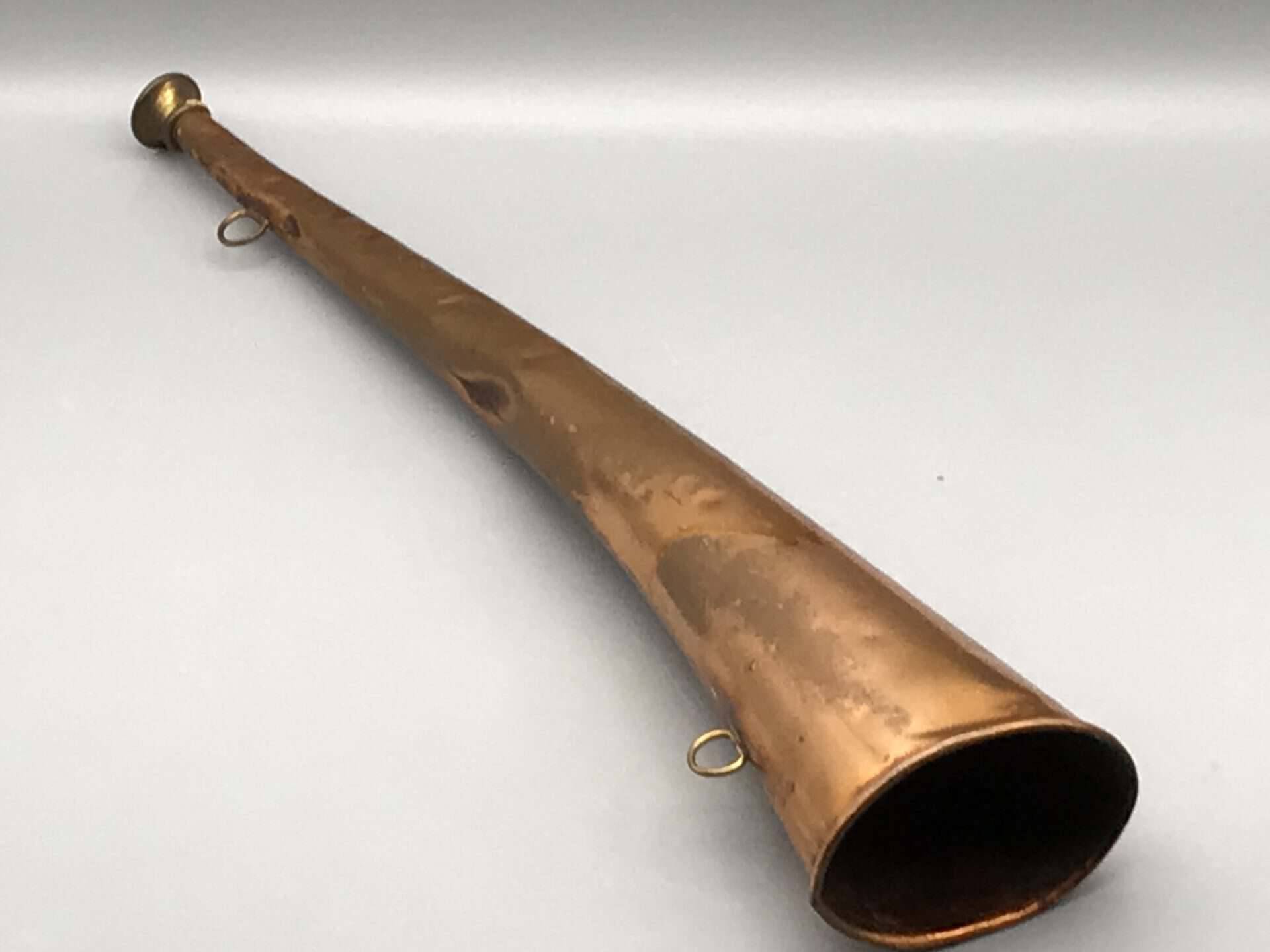 Antique copper hunting horn with brass fittings and original patina, measuring approximately 17 inches long.