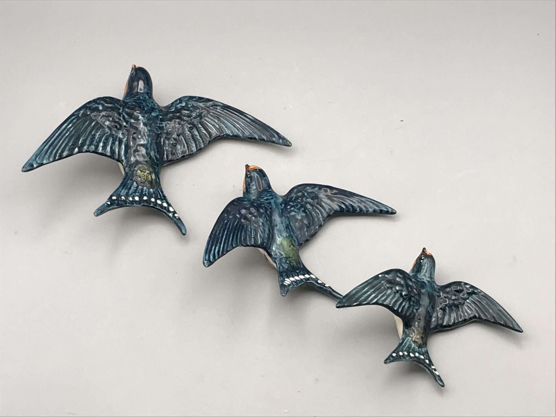 Top-down view of three vintage Beswick ceramic swallow wall plaques in graduated sizes
