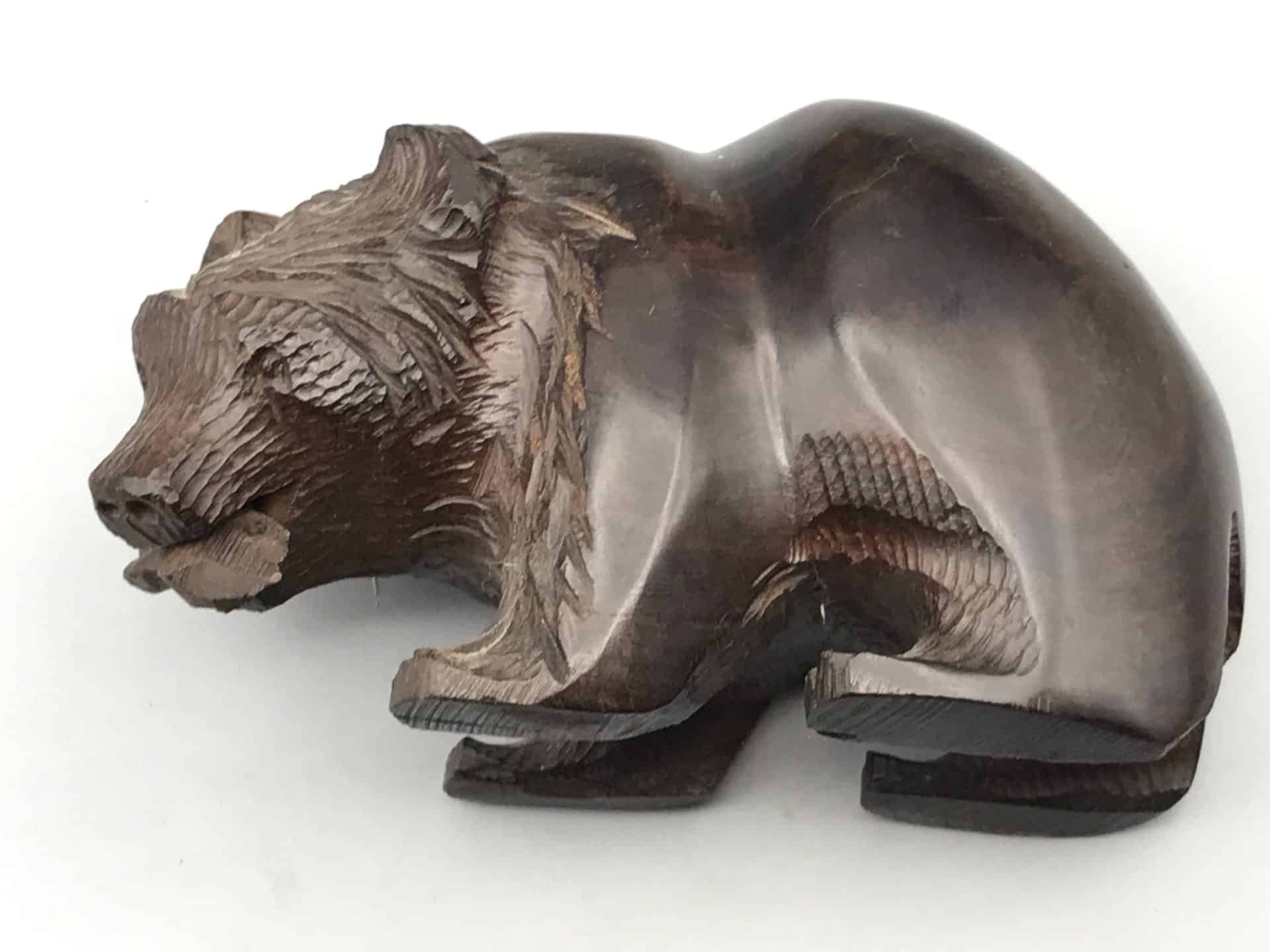 Hand-carved hardwood bear figure in Kibori Kuma style, shown from an angled top view with a fish in its mouth.