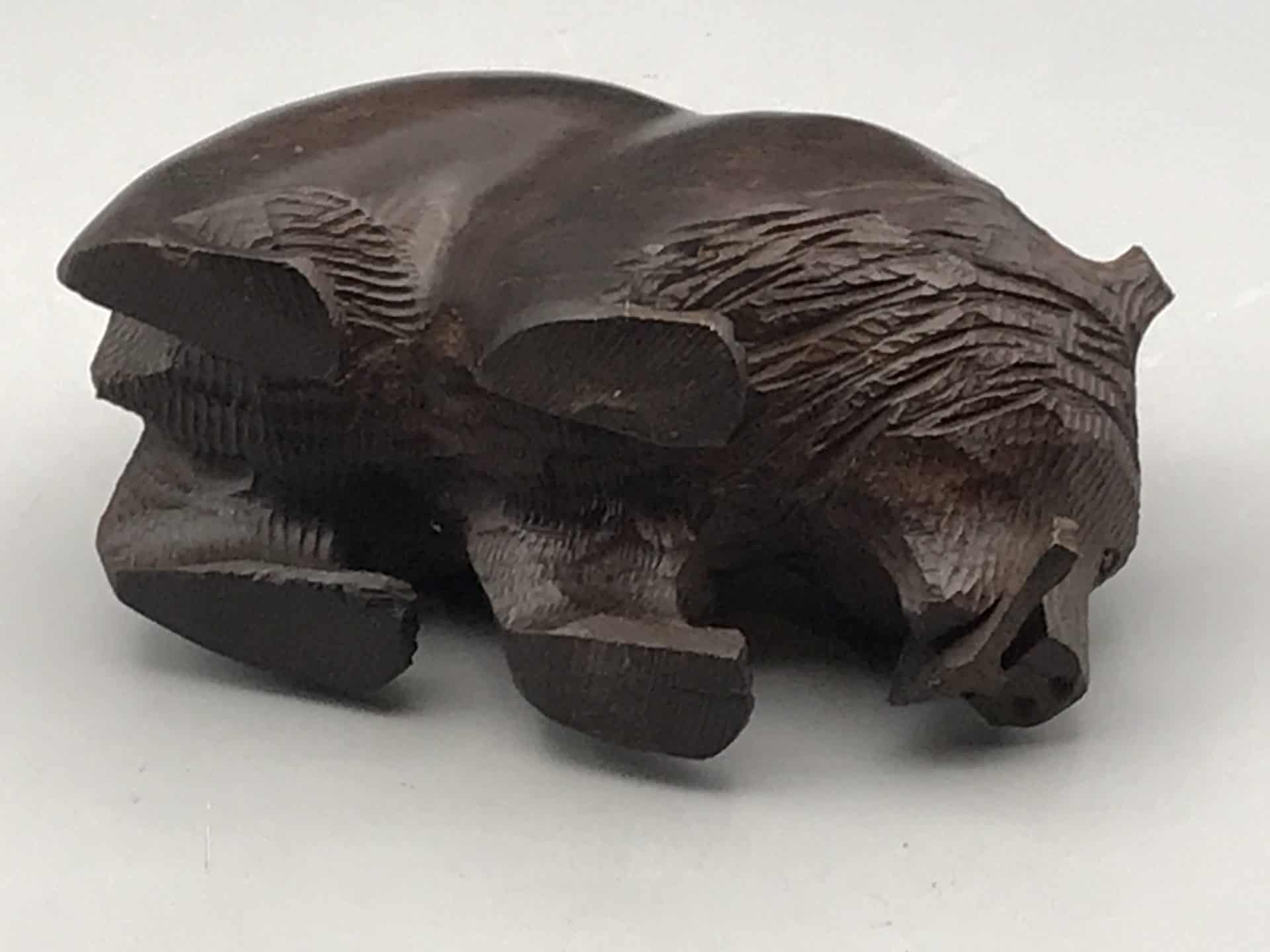 Underside view of a hand-carved hardwood bear in Kibori Kuma style, showing carved paws and fish detail.