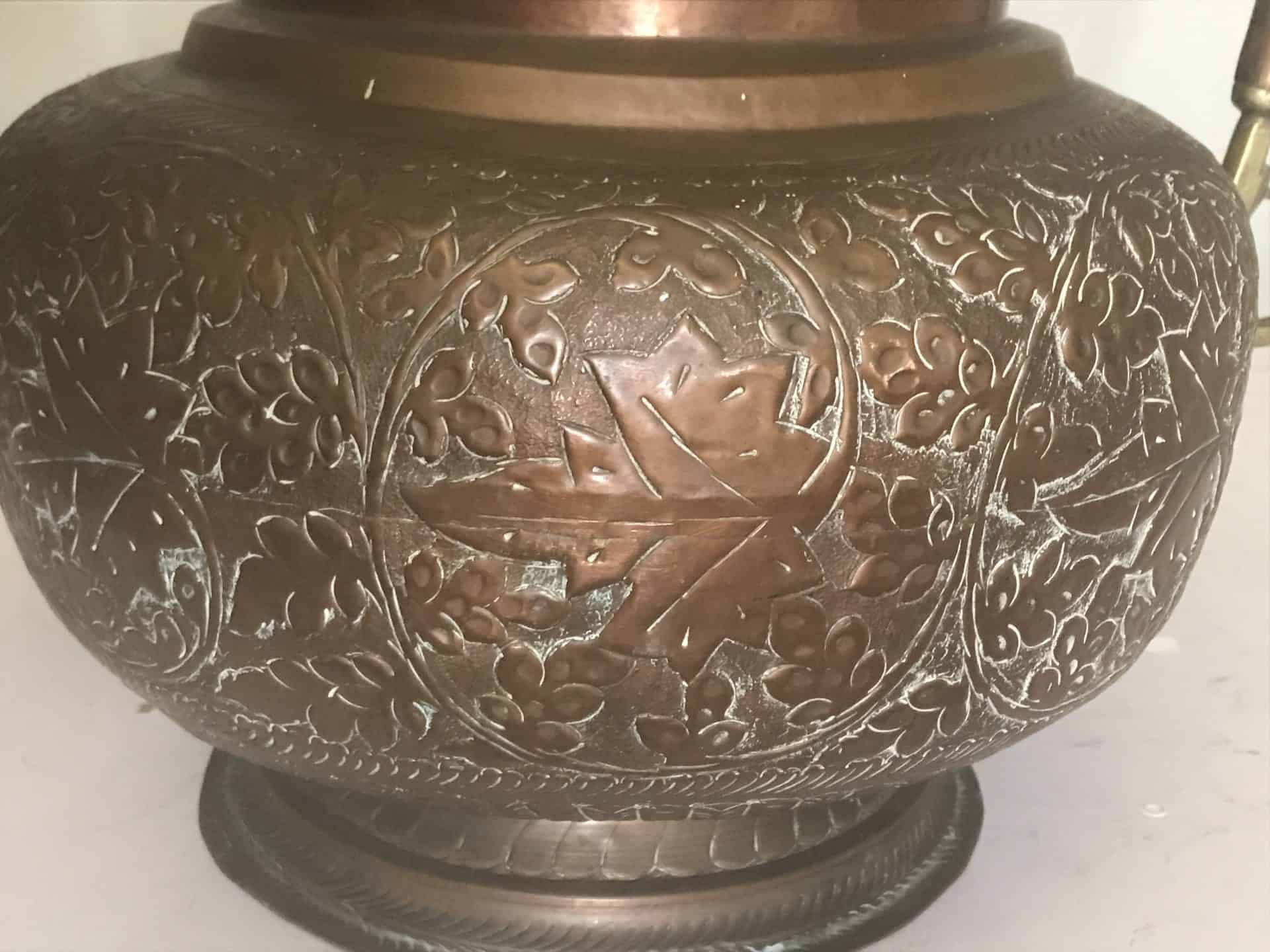 Close-up of the bulbous body of a monumental Ottoman copper ewer showing deep floral repoussé decoration with central medallion, late 19th century hand-raised metalwork