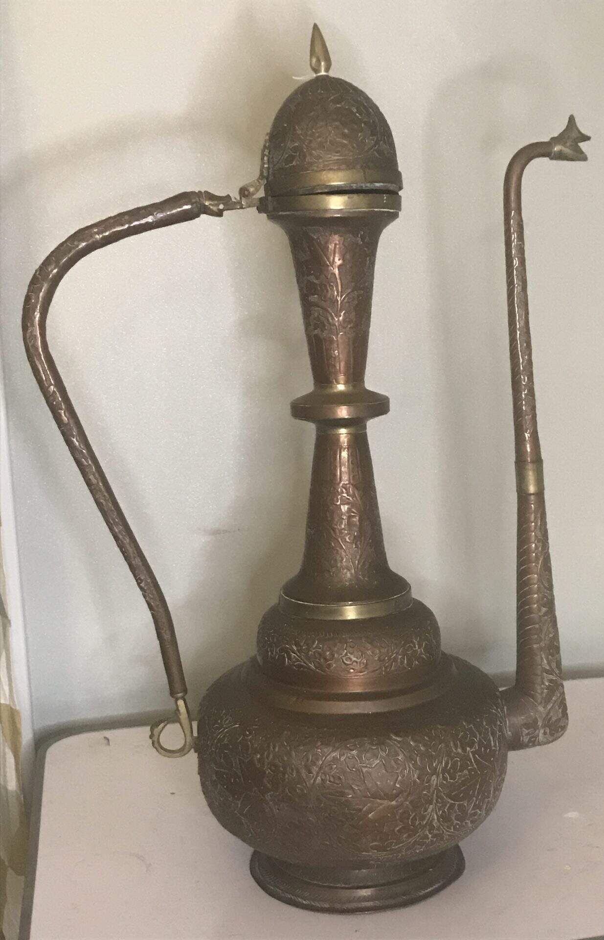 Rear view of a monumental late 19th century Ottoman copper ewer showing tall baluster neck, curved handle with ring terminal, and single swan-head spout