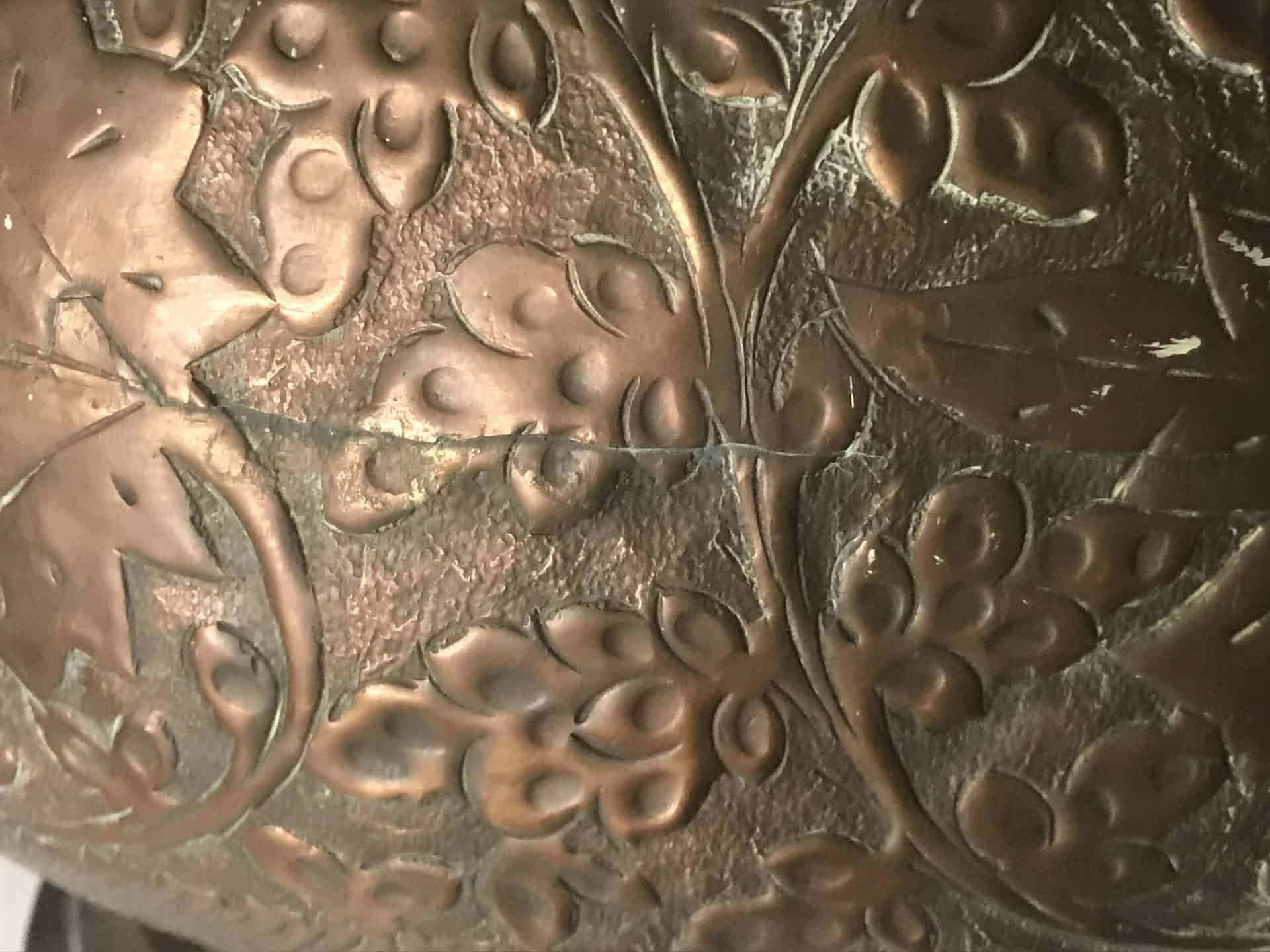 Close-up of the horizontal equator seam on a monumental Ottoman copper ewer showing aligned floral repoussé decoration and hand-soldered construction