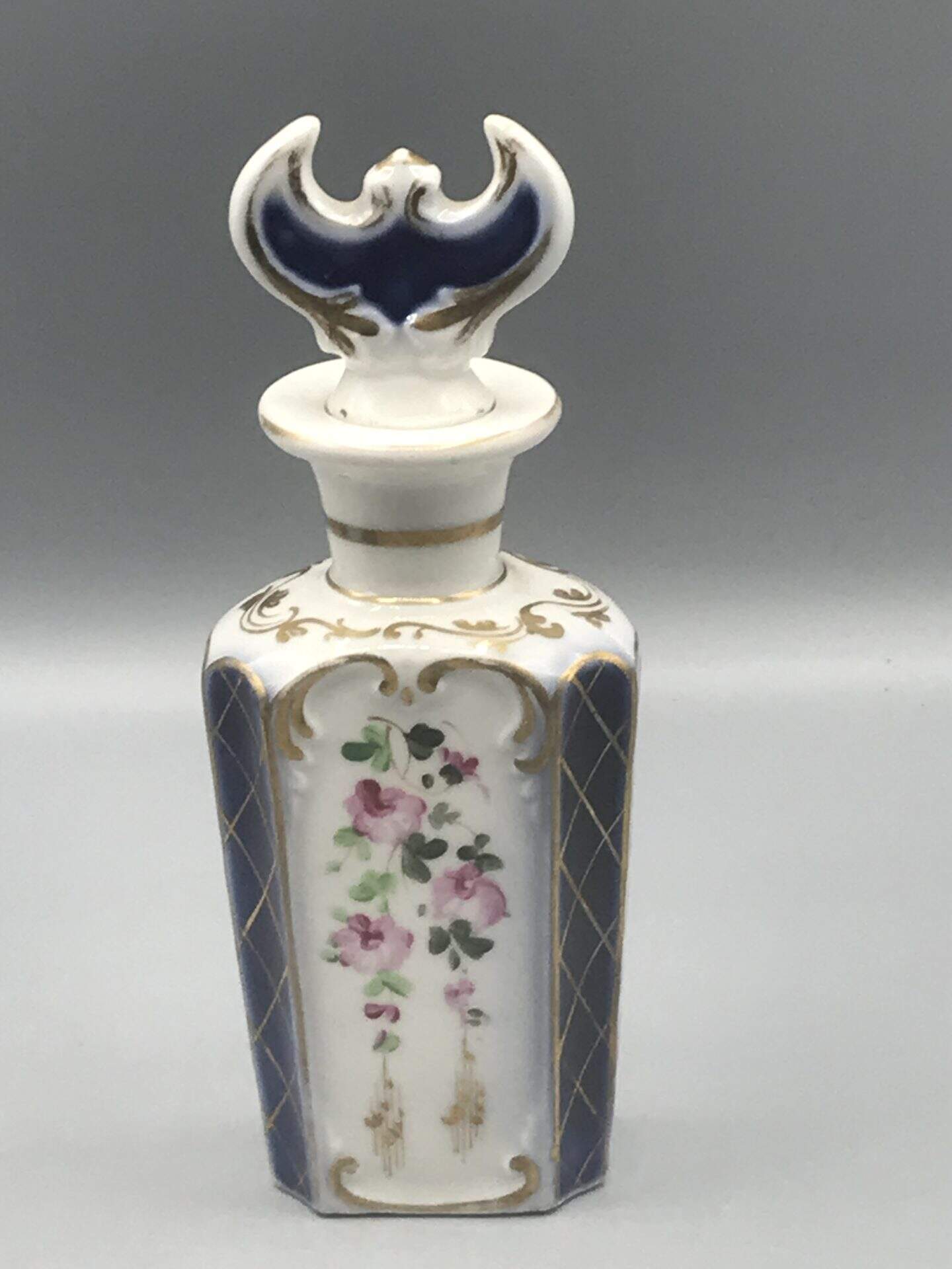 19th century French porcelain scent bottle with hand painted floral panels, cobalt blue ground, gilded decoration, and original porcelain stopper