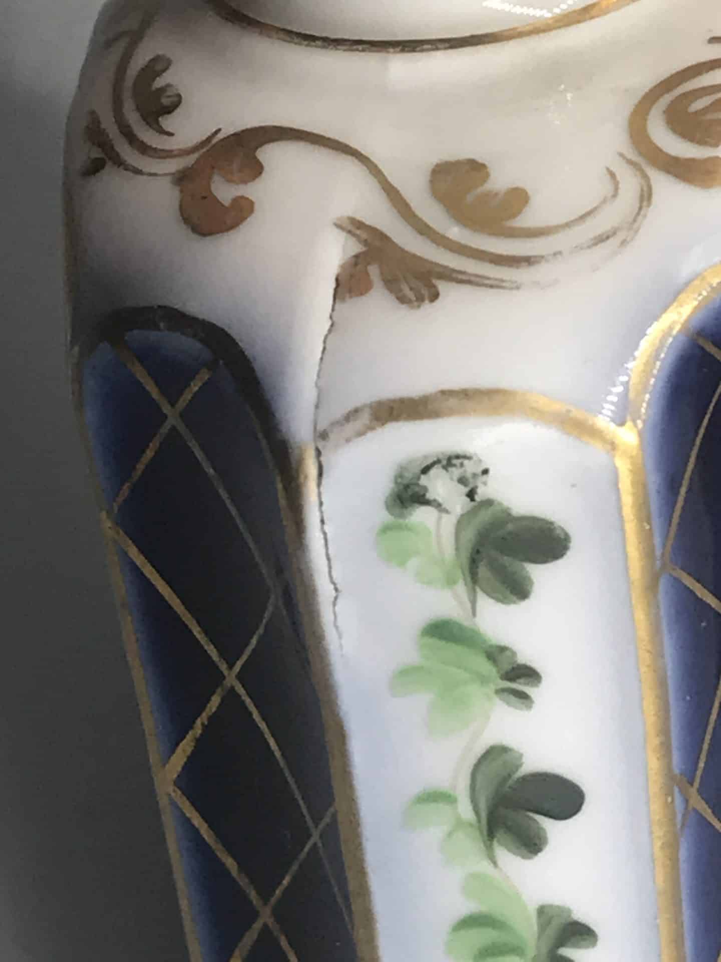 19th century French porcelain scent bottle detail showing hand painted floral panel, gilt scrollwork, and firing flaw crack on the shoulder